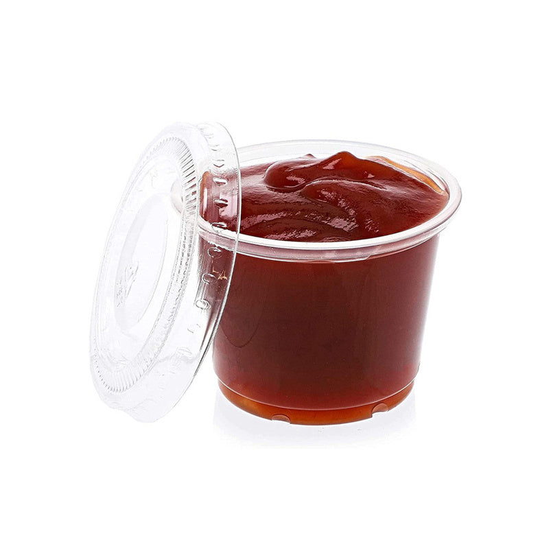 1 oz disposable plastic portion cup filled with ketchup beside a plastic lid
